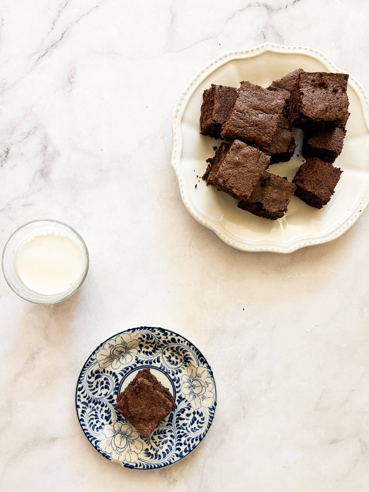 Effortless and gluten-free one bowl brownies are made in, yep, just one bowl. Just mix, pour, and bake to brownie perfection. A cup of milk, a brownie on a plate, and a plate of more brownies.