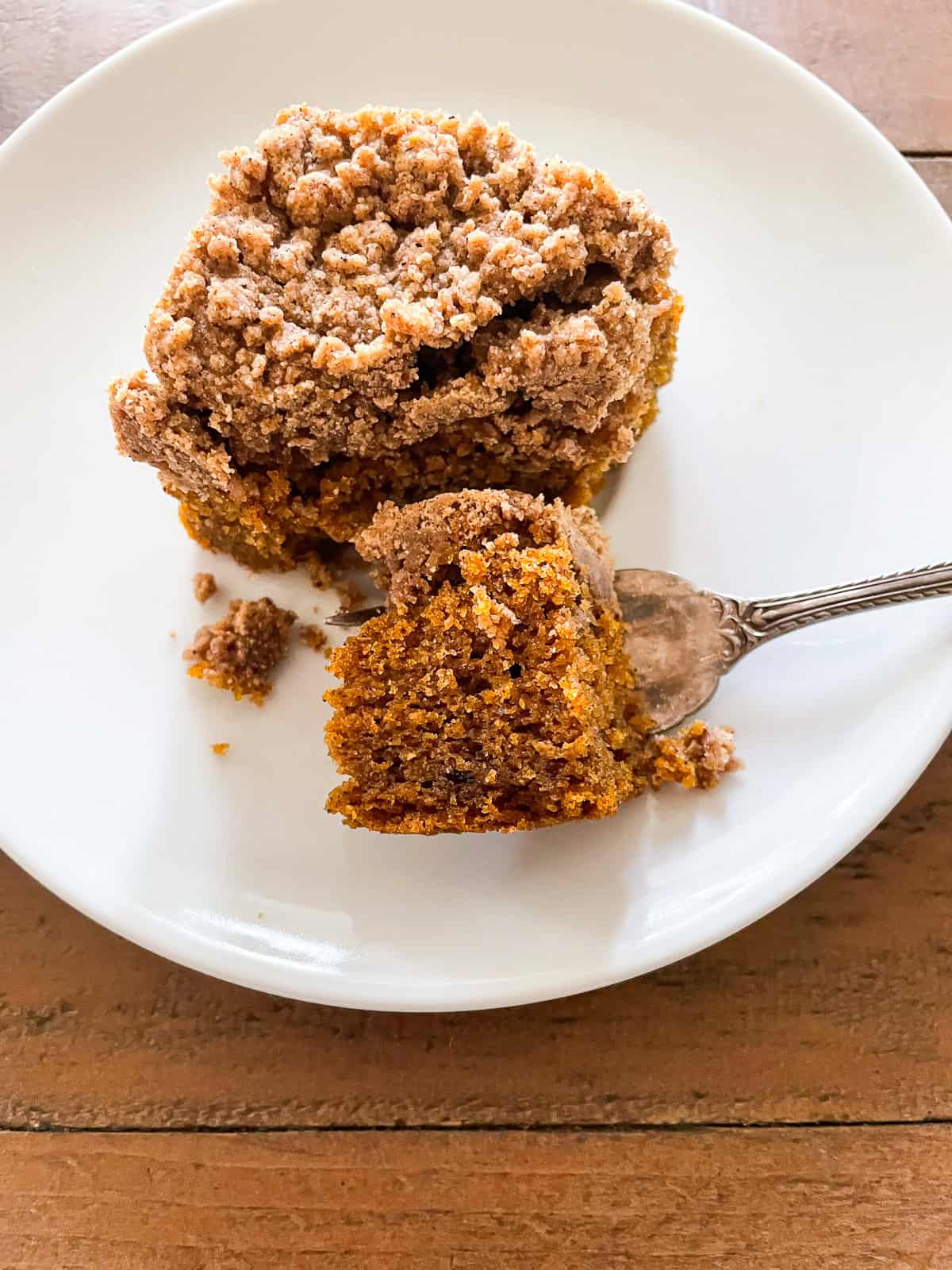 The perfect fall treat, this sweetly spiced and tender gluten free pumpkin coffee cake is topped with a delicious brown sugar streusel. A bite of pumpkin coffee cake on a fork.