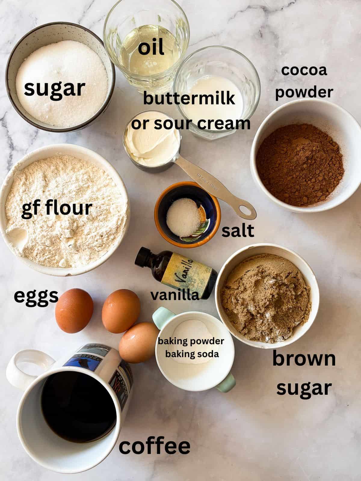 This gluten-free chocolate cake is a deeply dark chocolate cake with a soft and tender crumb that's perfect with fluffy chocolate buttercream. The ingredients for a gluten-free chocolate cake are text-labeled and portioned out.