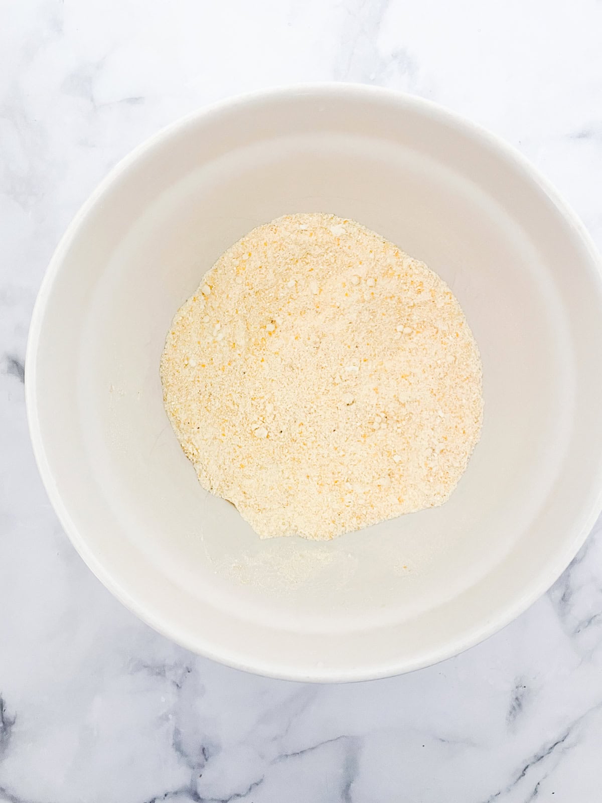 Easy, gluten-free almond flour cornbread is made with a combo of almond flour and cornmeal. Wonderful with soups, stews, chili, and more. The dry mix for almond flour cornbread in a bowl.