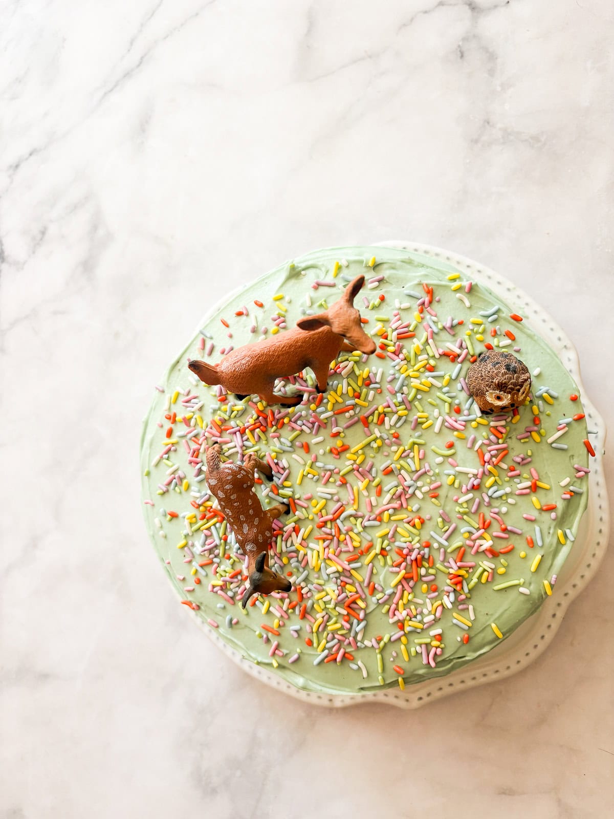 This is the best chocolate cake: Moist, tender, and with a perfect gluten-free crumb! Top it with chocolate buttercream for a real treat. Little deer decorate the top of the best chocolate cake ever.