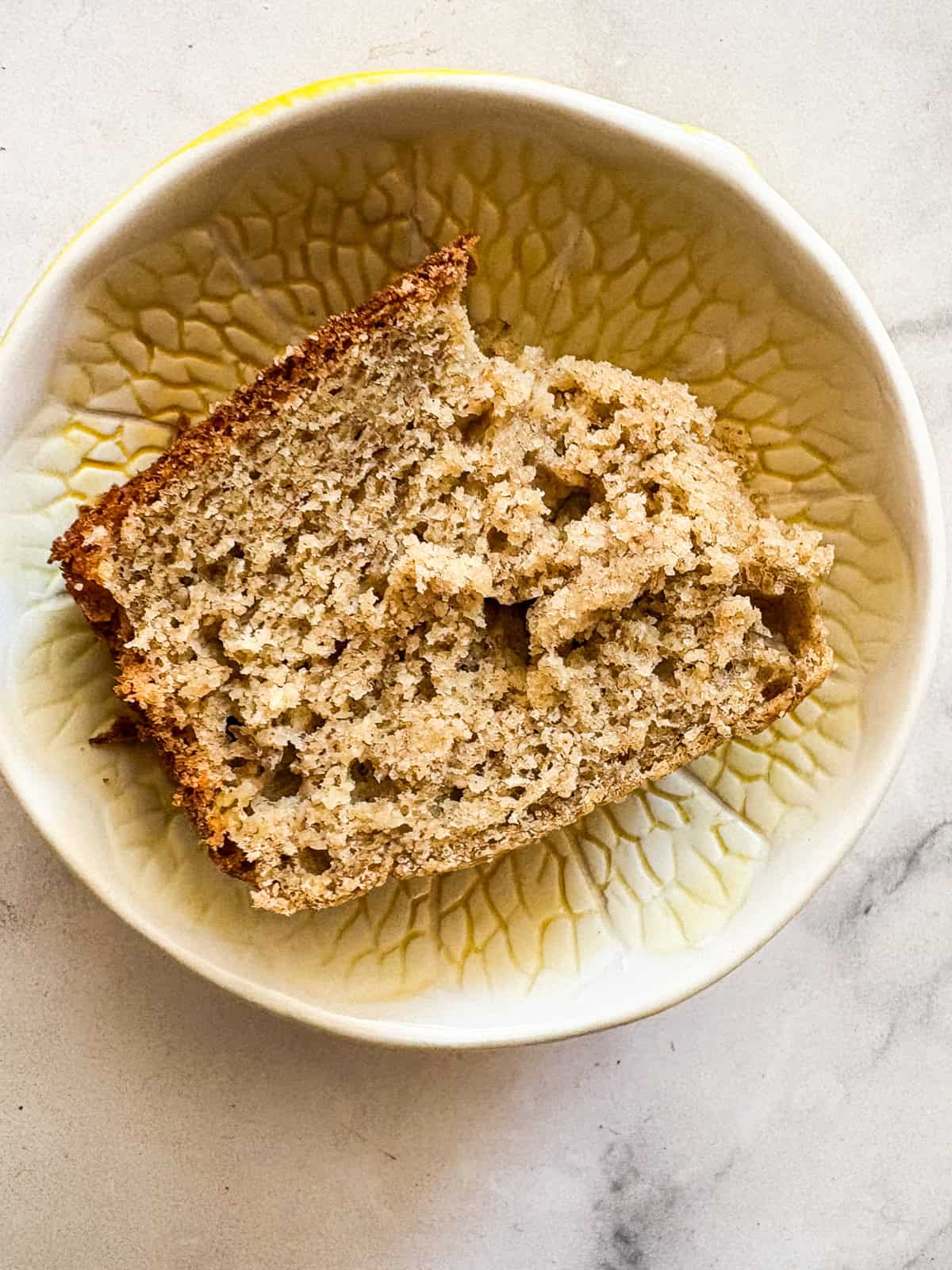 Perfect-every-time, super easy, beyond comforting and cozy gluten-free banana bread is made in just one bowl and bakes up like a dream. A slice of gluten free banana bread in a decorative bowl.