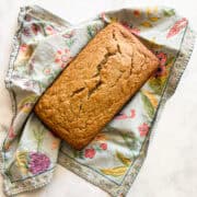 A loaf of gluten free banana bread on a pretty napkin.