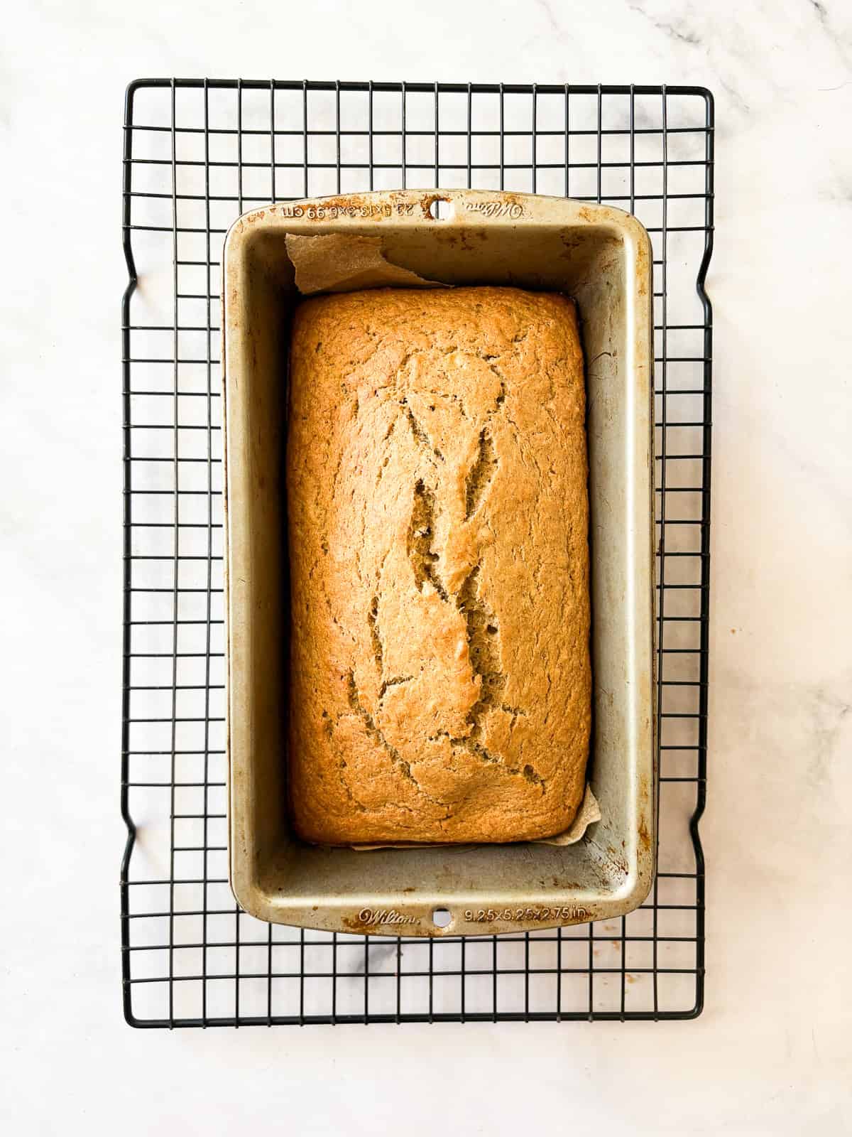 Perfect-every-time, super easy, beyond comforting and cozy gluten-free banana bread is made in just one bowl and bakes up like a dream. A loaf of gluten free banana bread cools in the tin on a wire rack.