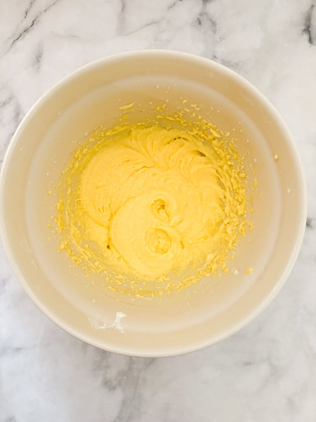 This gluten free blackberry cake features a plush vanilla cake swirled with juicy berries! Delicious and beautiful. Butter, sugar, and eggs mixed in a bowl.