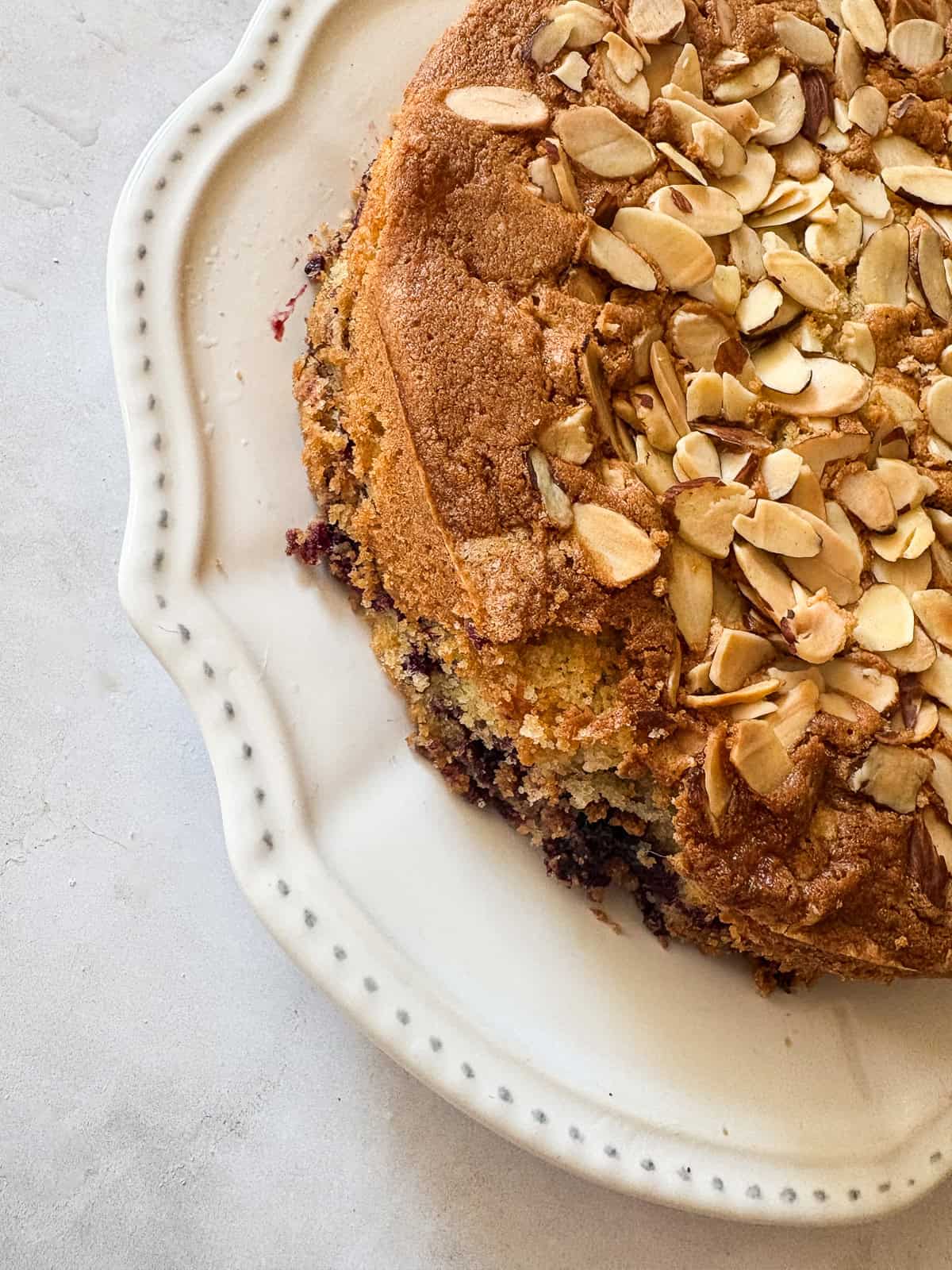 This gluten free blackberry cake features a plush vanilla cake swirled with juicy berries! Delicious and beautiful. Blackberries peek out of the side of a gluten free blackberry cake.