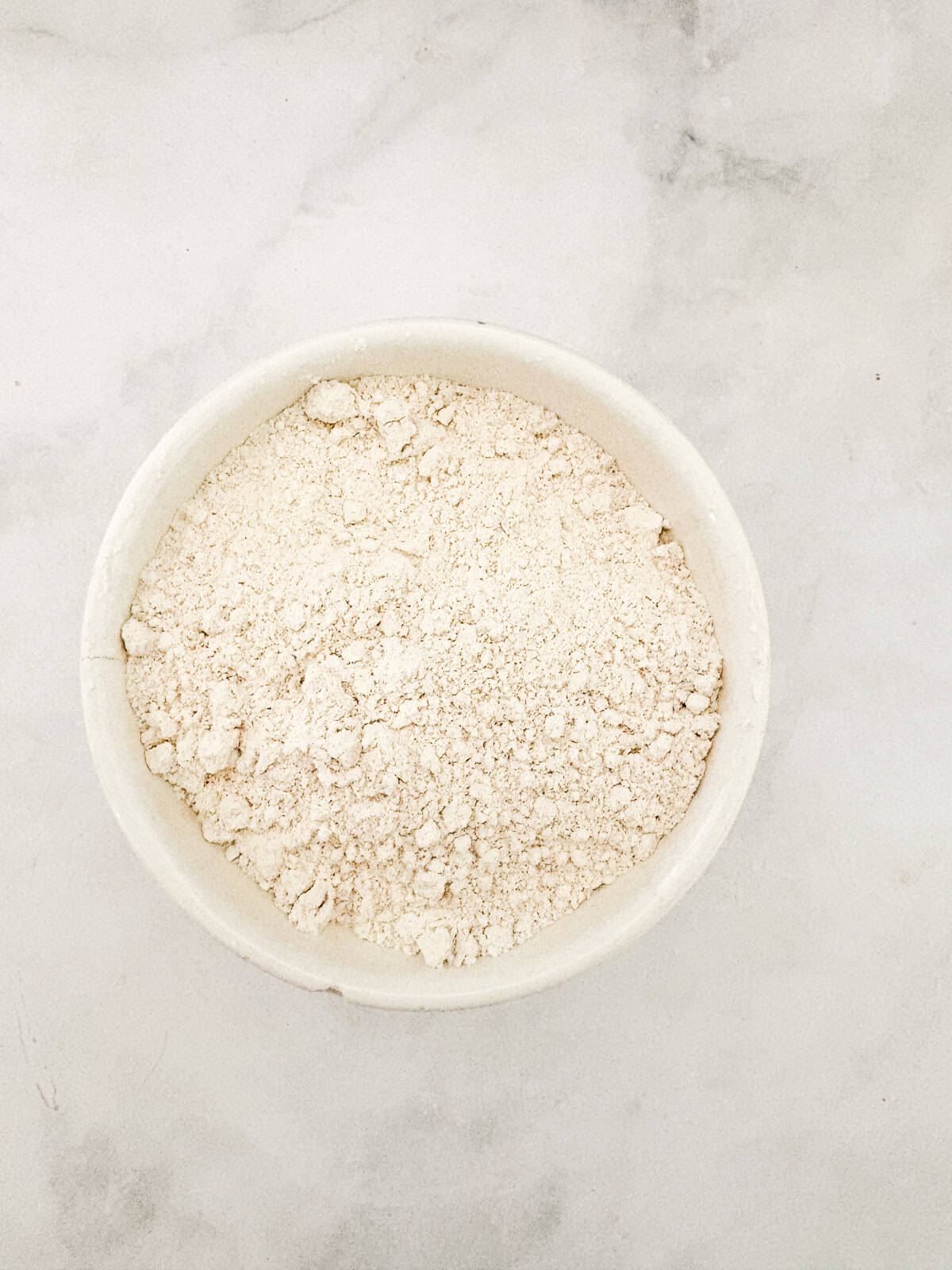 This gluten free blackberry cake features a plush vanilla cake swirled with juicy berries! Delicious and beautiful. Flour whisked with baking powder and salt in a bowl.