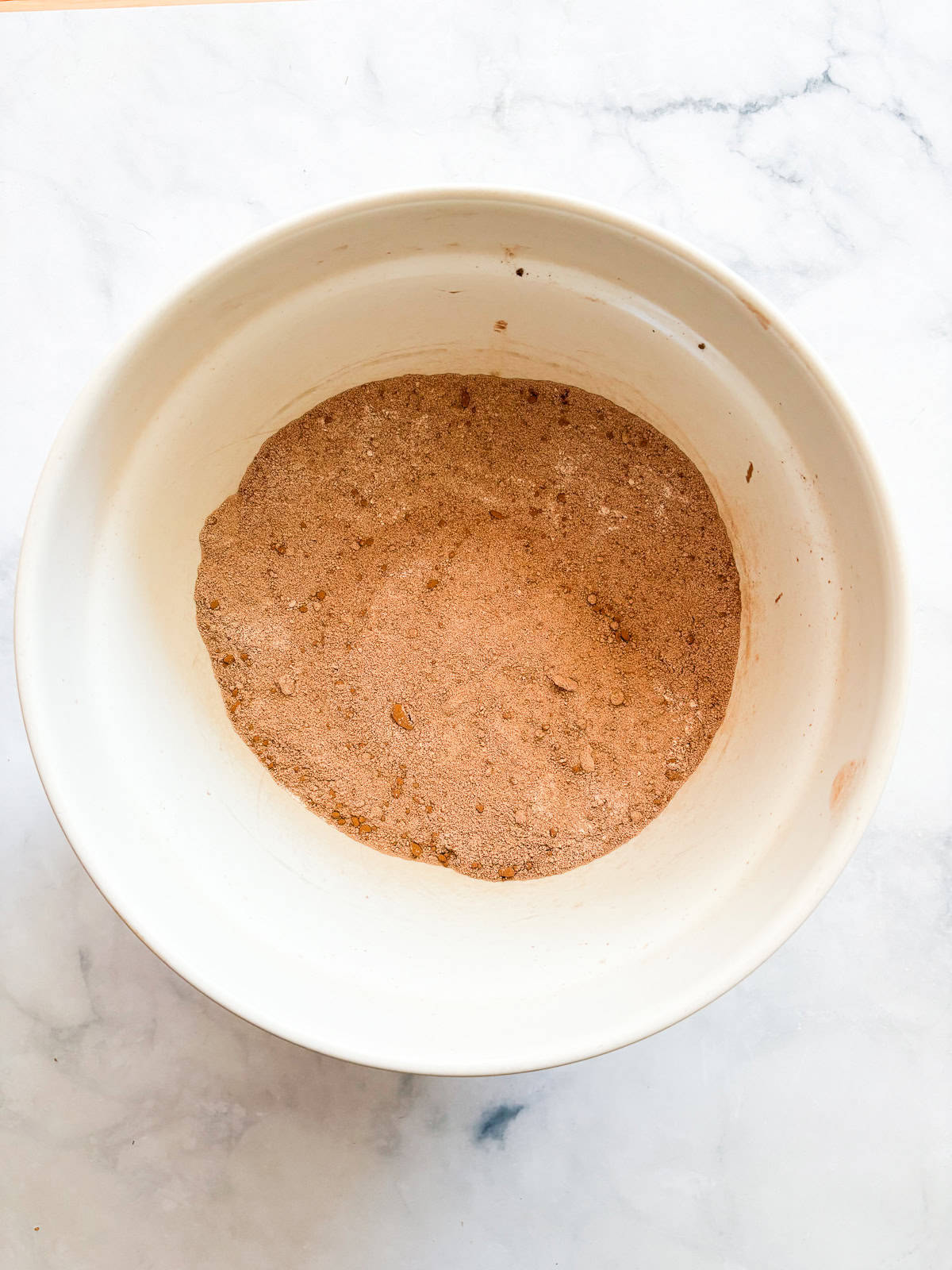 This gluten-free chocolate cake is a deeply dark chocolate cake with a soft and tender crumb that's perfect with fluffy chocolate buttercream. Dry mix for gluten-free chocolate cake in a bowl.
