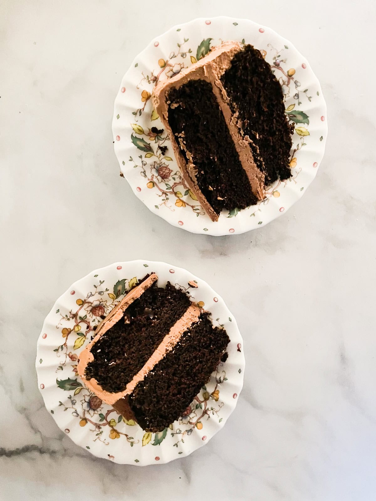 This gluten-free chocolate cake is a deeply dark chocolate cake with a soft and tender crumb that's perfect with fluffy chocolate buttercream. Slices of gluten-free chocolate cake on plates.