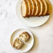 A sliced loaf of gluten free coconut banana bread on a plate with a slice on a plate next to it.