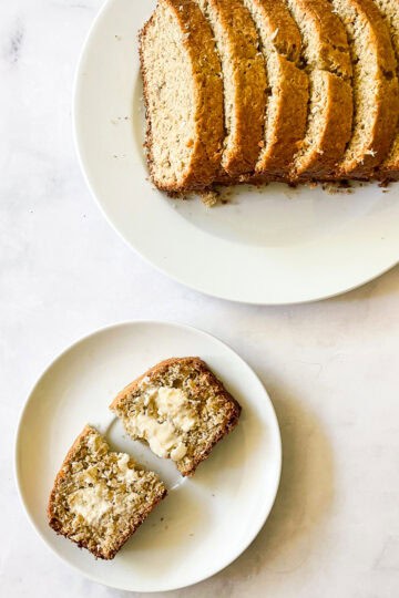 A sliced loaf of gluten free coconut banana bread on a plate with a slice on a plate next to it.