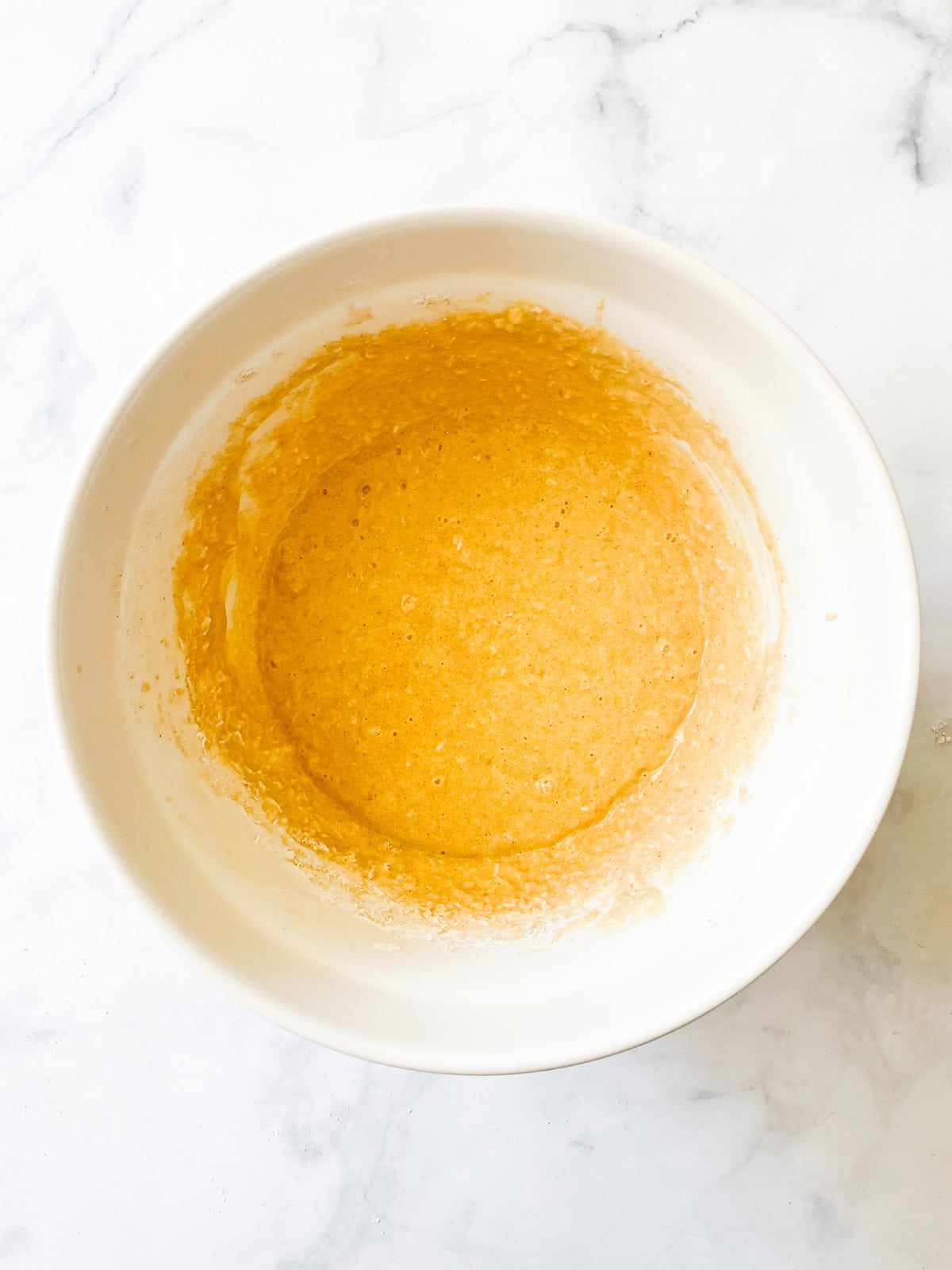 This recipe for gluten free coconut banana bread produces a beautiful loaf with a dense, moist crumb that's swirled with shredded coconut. Combined batter for coconut banana bread in a bowl.