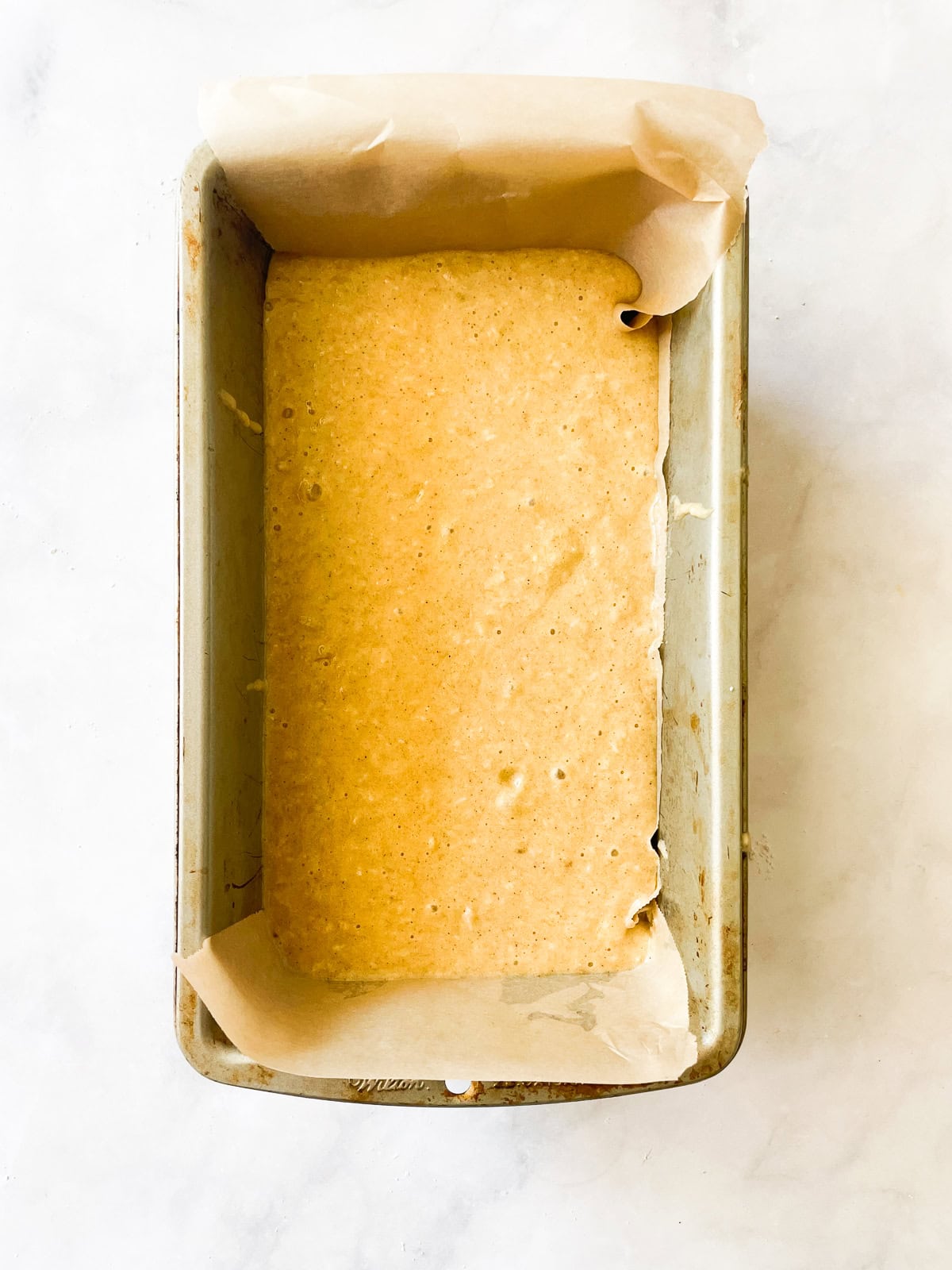 This recipe for gluten free coconut banana bread produces a beautiful loaf with a dense, moist crumb that's swirled with shredded coconut. Batter for coconut banana bread in a loaf pan.