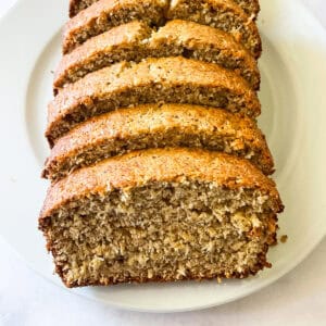 A plate with a sliced loaf of gluten free coconut banana bread.