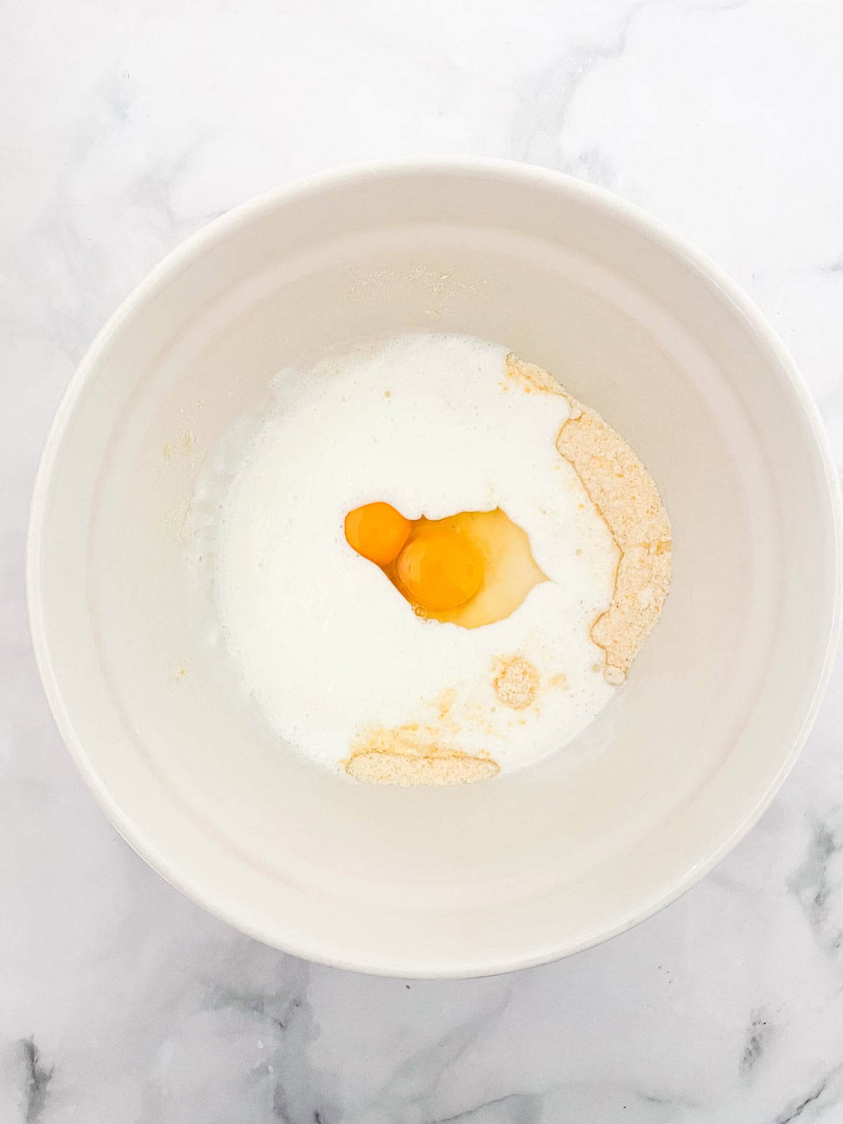 This gluten-free maple cornbread is tender-crumbed perfection thanks to buttermilk. Naturally sweetened with pure maple syrup! Eggs mixed with milk in a bowl.