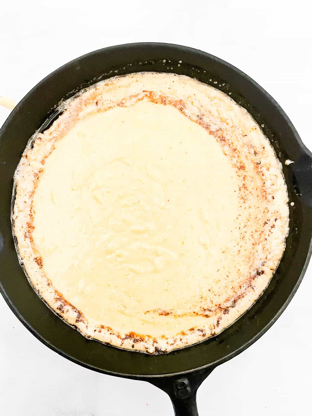 This gluten-free maple cornbread is tender-crumbed perfection thanks to buttermilk. Naturally sweetened with pure maple syrup! Cornbread batter is added to a cast iron pan.