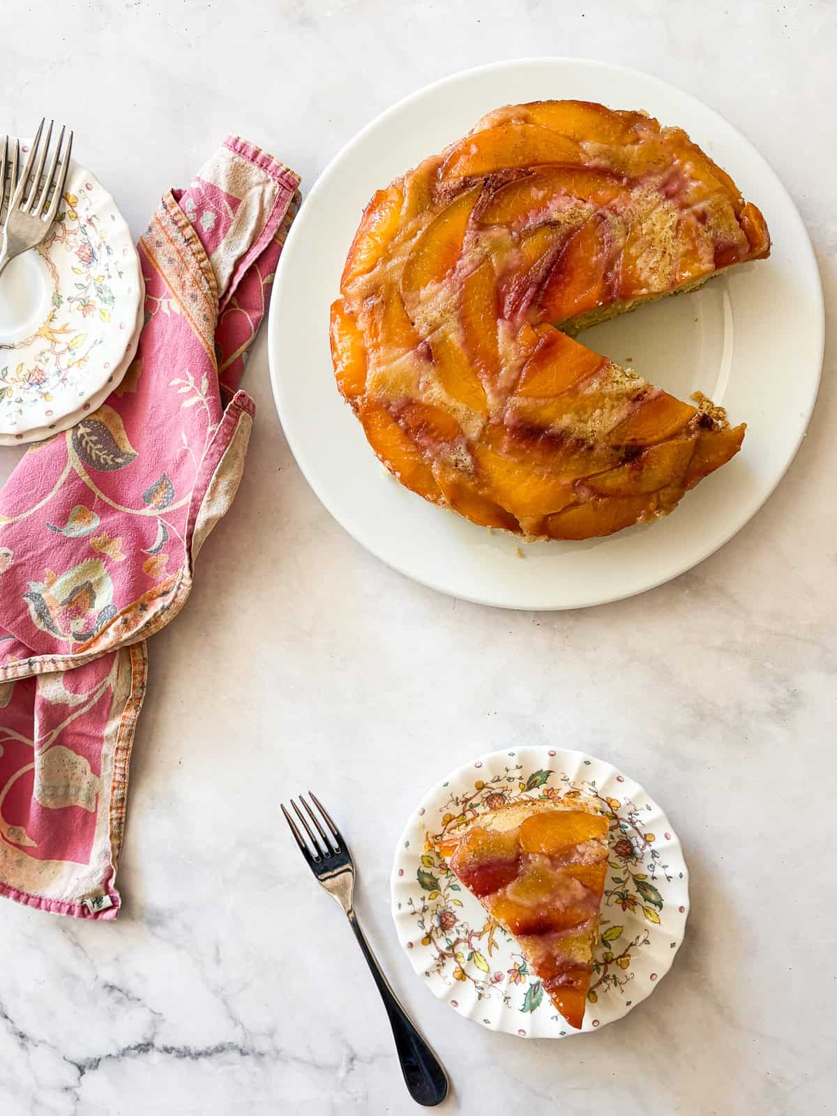 This gluten free nectarine cake is as pretty as it is delicious! Juicy sliced nectarines top a soft and sweet vanilla cake. A slice of gluten free nectarine cake on a plate and the cake behind it.