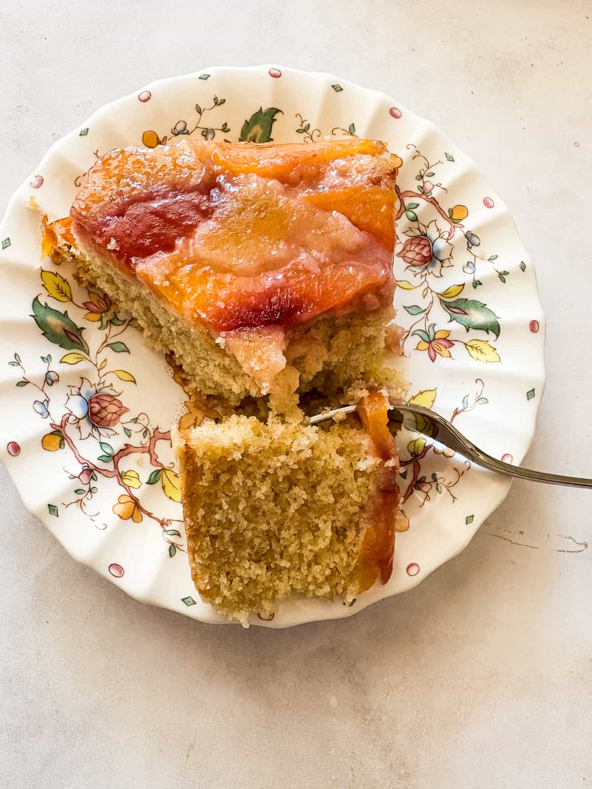 This gluten free nectarine cake is as pretty as it is delicious! Juicy sliced nectarines top a soft and sweet vanilla cake. A fork cuts into a slice of gluten free nectarine cake.