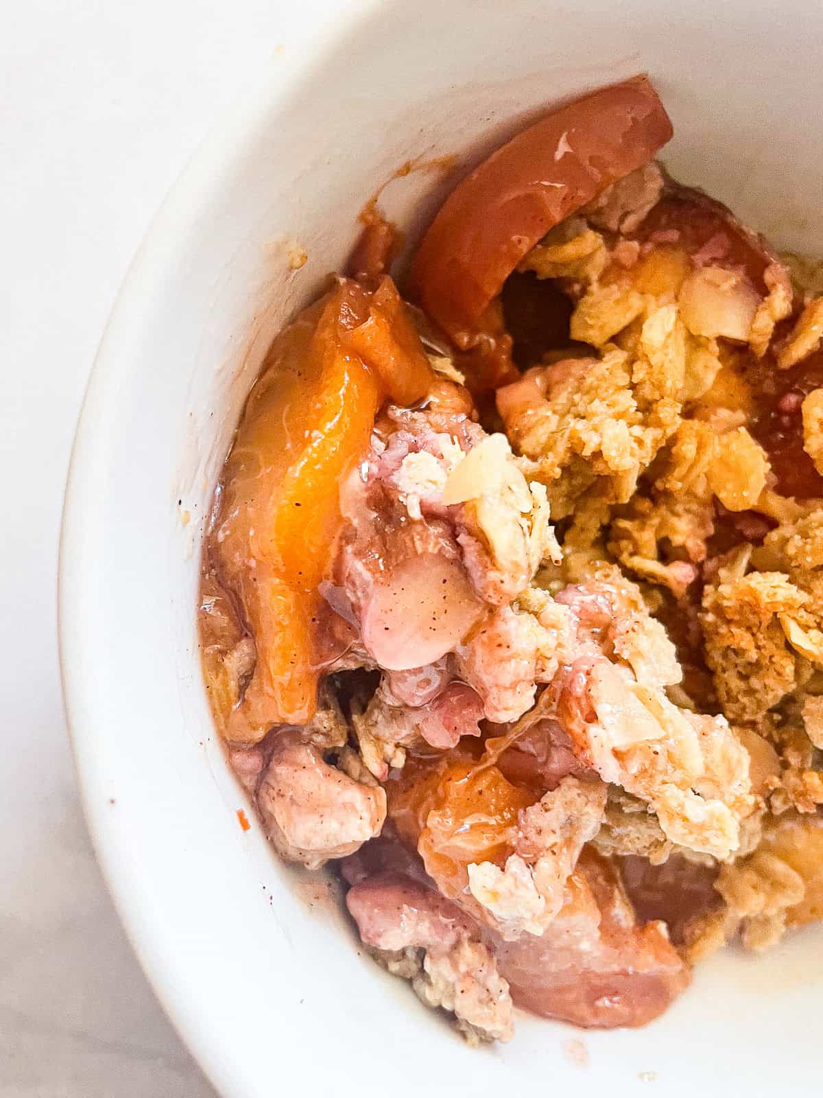 This beautifully simple gluten free nectarine crisp highlights ripe summer stone fruit. Add fresh rosemary for a lovely herbal touch. A bowl of gluten free nectarine crisp.