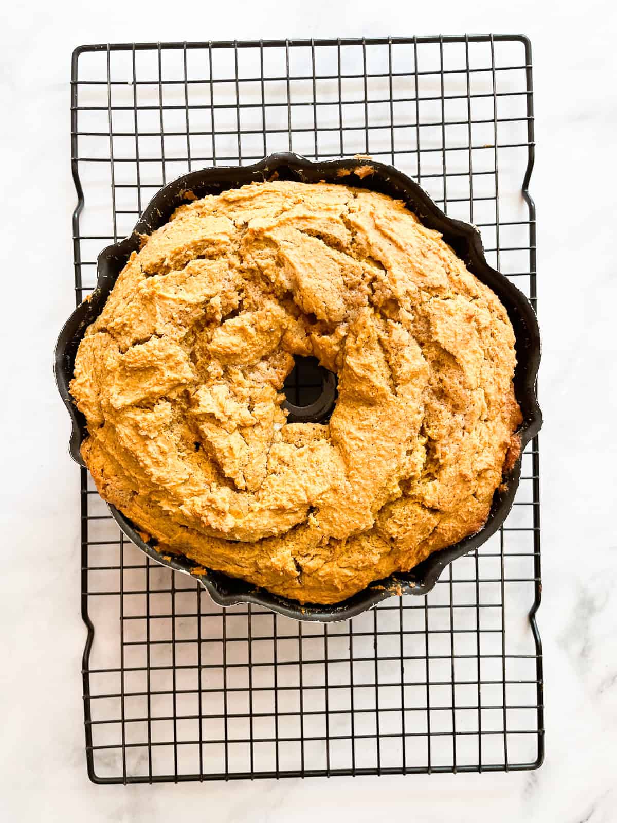 A soft and sumptuous gluten free pumpkin donut cake is bathed in cinnamon-sugar for a fabulous fall treat. A gluten free pumpkin donut bundt cake cools in a pan.