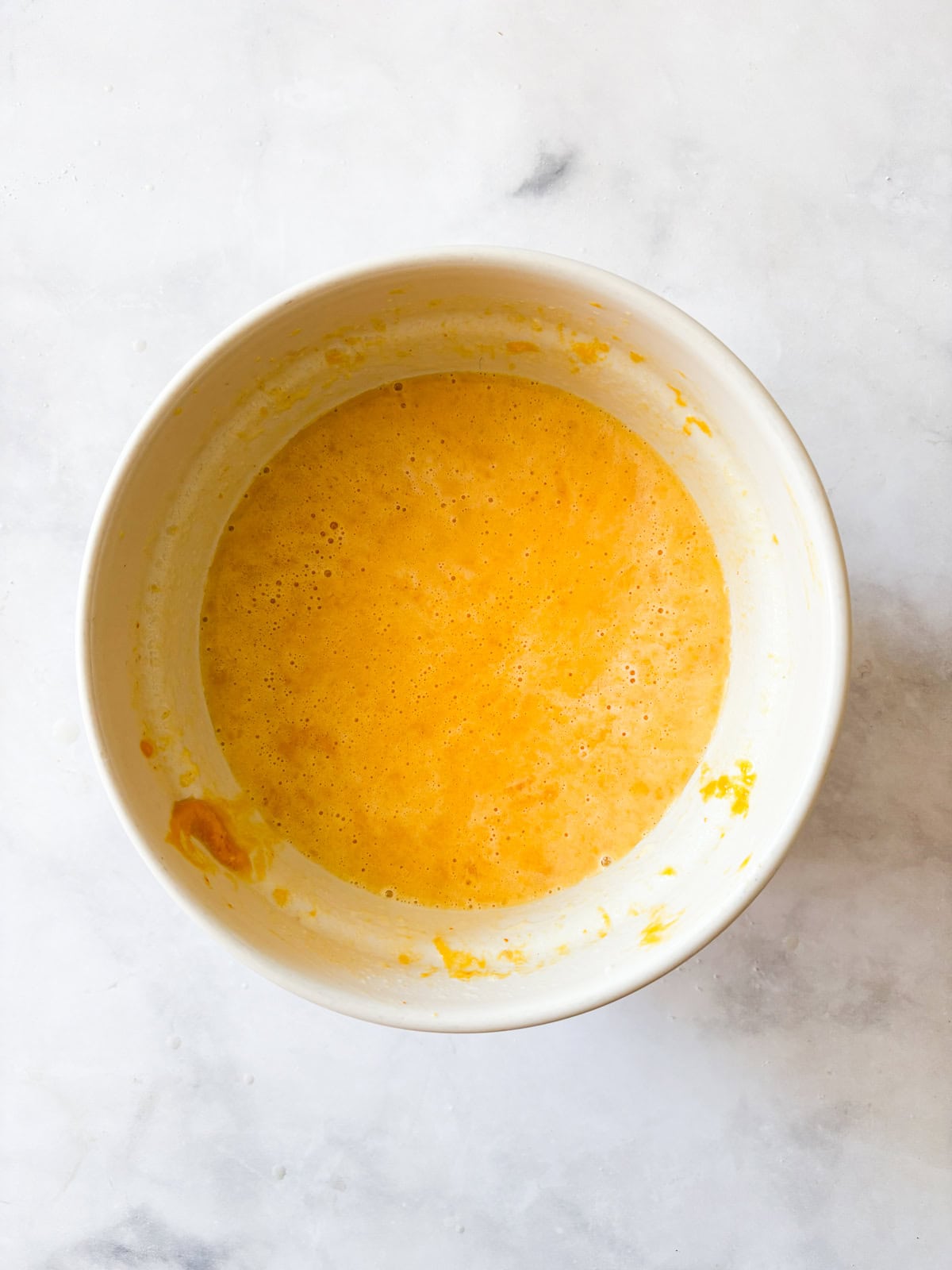 Soft and fluffy gluten free pumpkin pancakes are packed with plenty of fall flavor thanks to pumpkin puree, warming spices, and maple syrup! Eggs, butter, milk, and pumpkin mixed in a bowl.