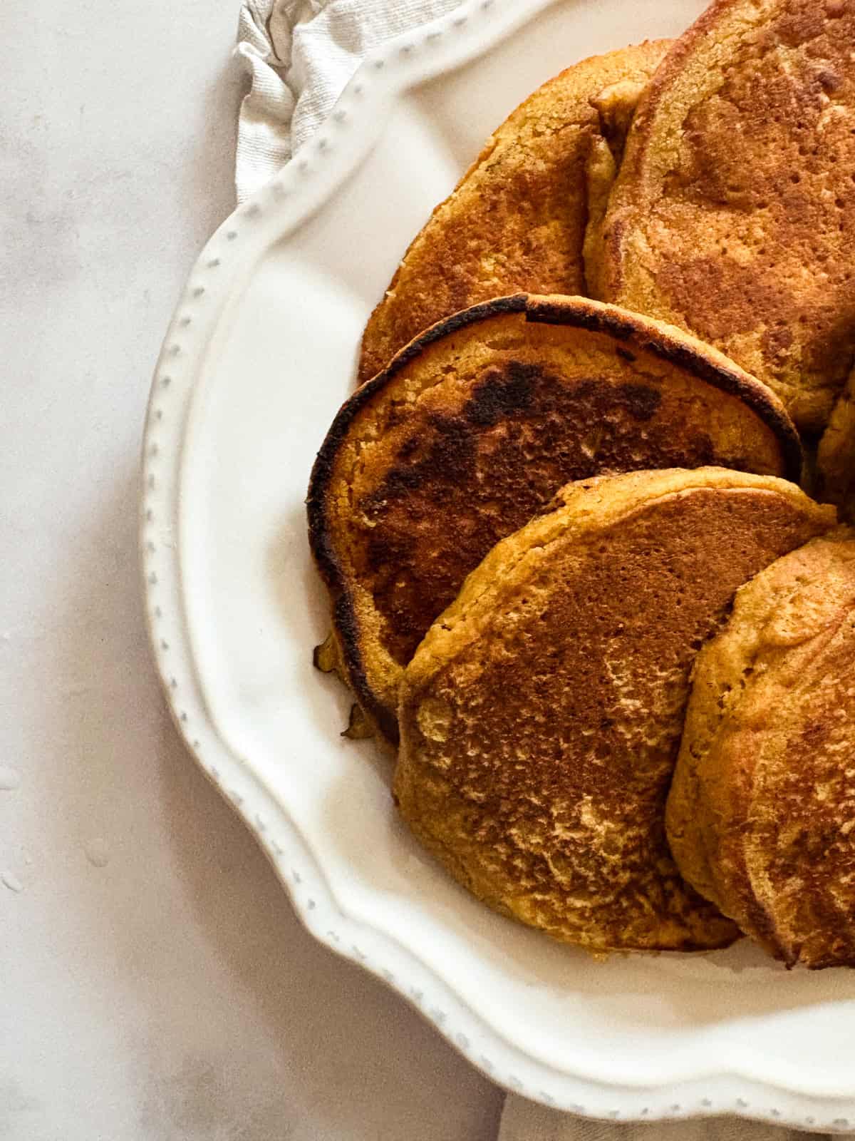 Gluten free pumpkin pancakes are arranged on a plate.