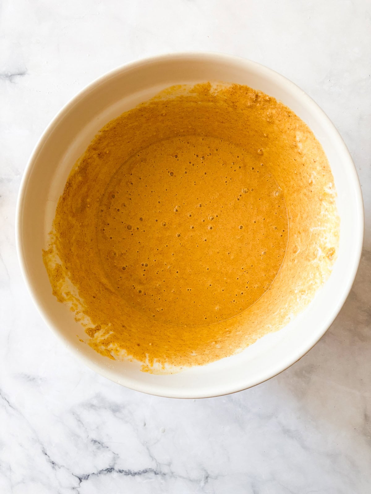 Soft and fluffy gluten free pumpkin pancakes are packed with plenty of fall flavor thanks to pumpkin puree, warming spices, and maple syrup! Gluten free pumpkin pancakes batter in a bowl.