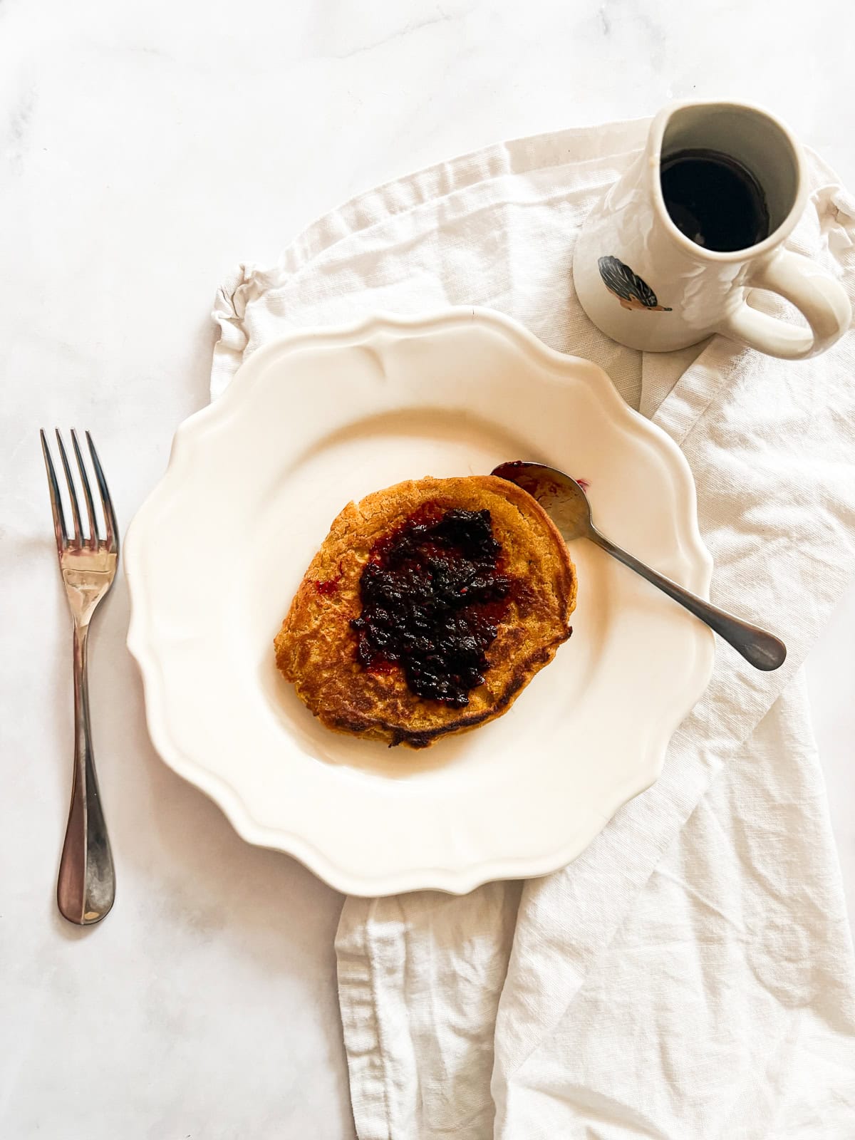 Soft and fluffy gluten free pumpkin pancakes are packed with plenty of fall flavor thanks to pumpkin puree, warming spices, and maple syrup! Blackberry jam spread on a gluten free pumpkin pancake.