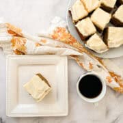 A slice of gluten free pumpkin snack on a plate with a cup of coffee.