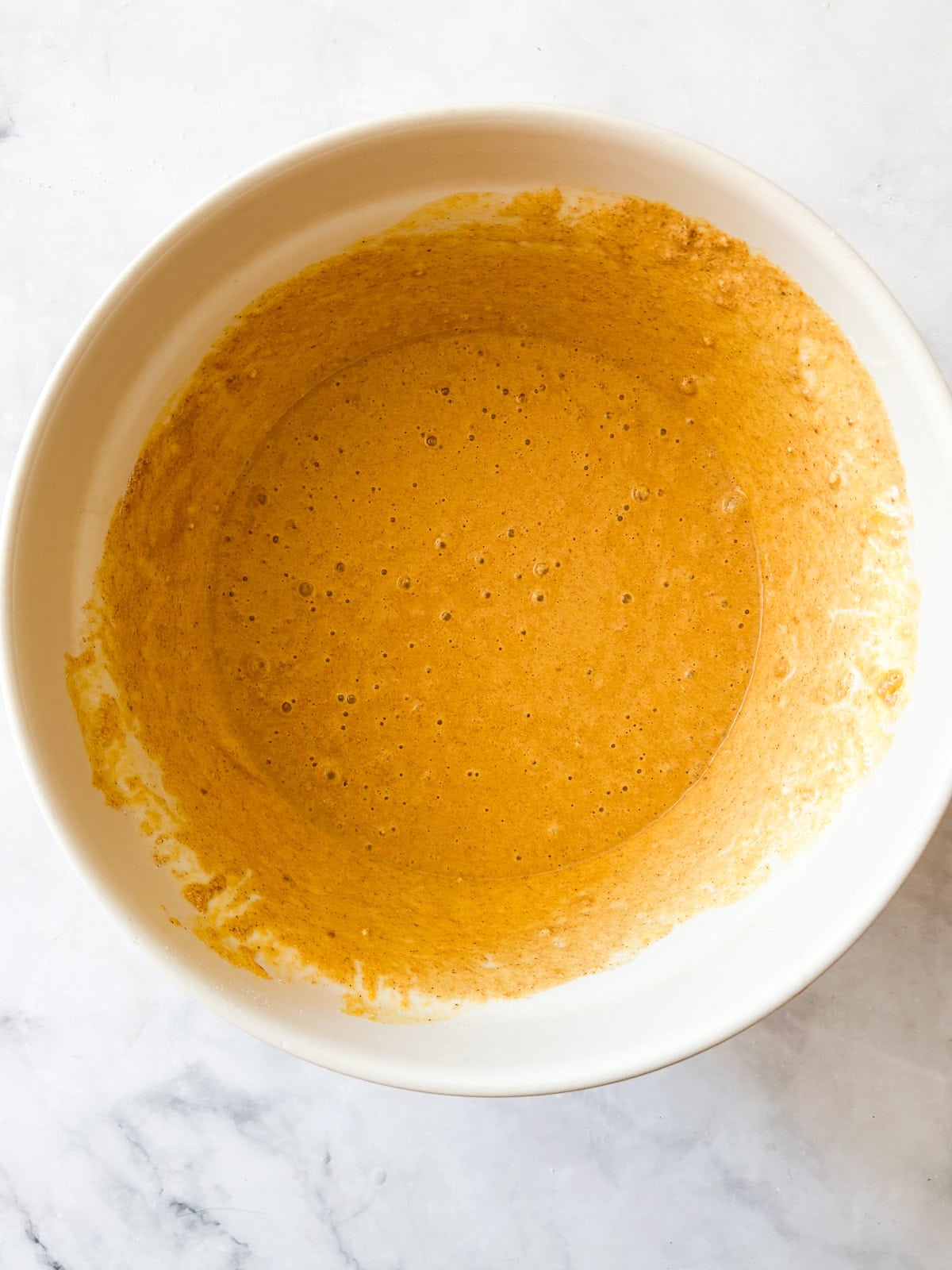 Warmly spiced and naturally gluten-free pumpkin waffles are what you want on a crisp fall morning. Made with whole grain oat flour! Pumpkin waffle batter in a bowl.