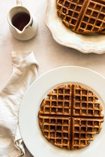A plate of pumpkin waffles and syrup.
