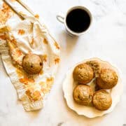 A pretty napkin next to gluten free zucchini chocolate chip muffins and coffee.