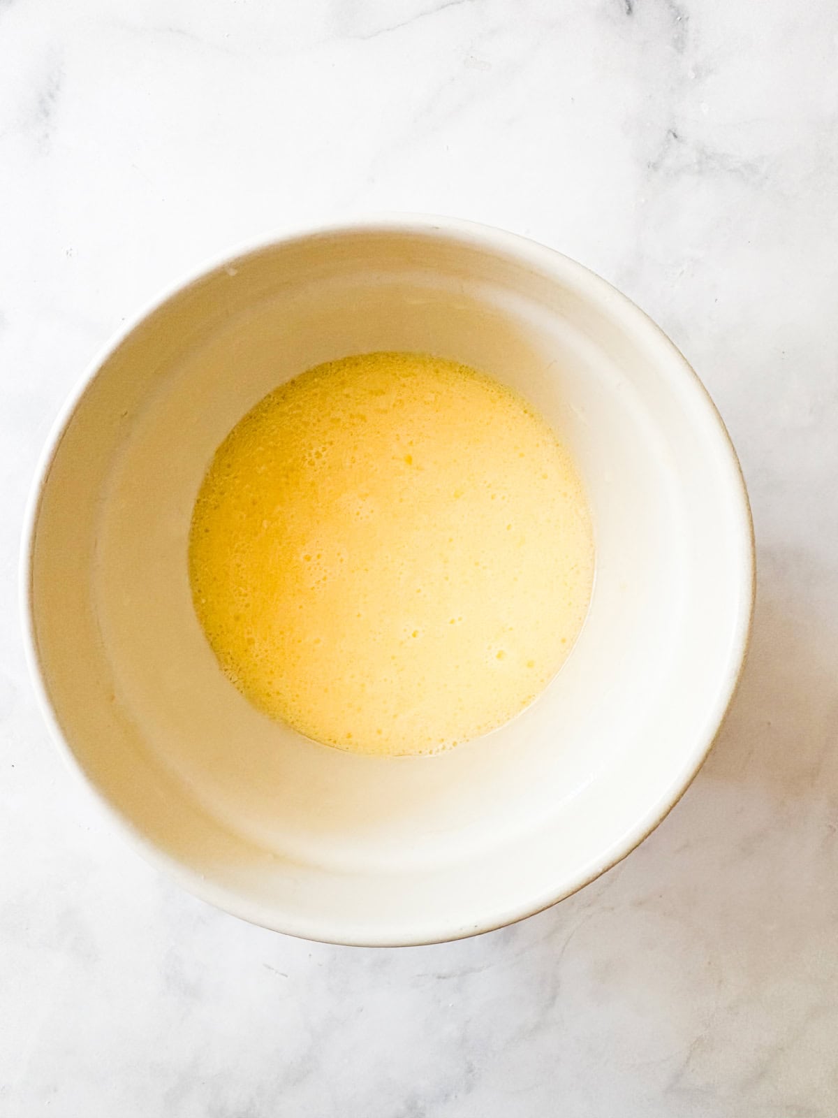 Tuck shredded squash into these gluten free zucchini chocolate chip muffins for a delectable morning treat. Eggs and oil are whisked in a bowl.