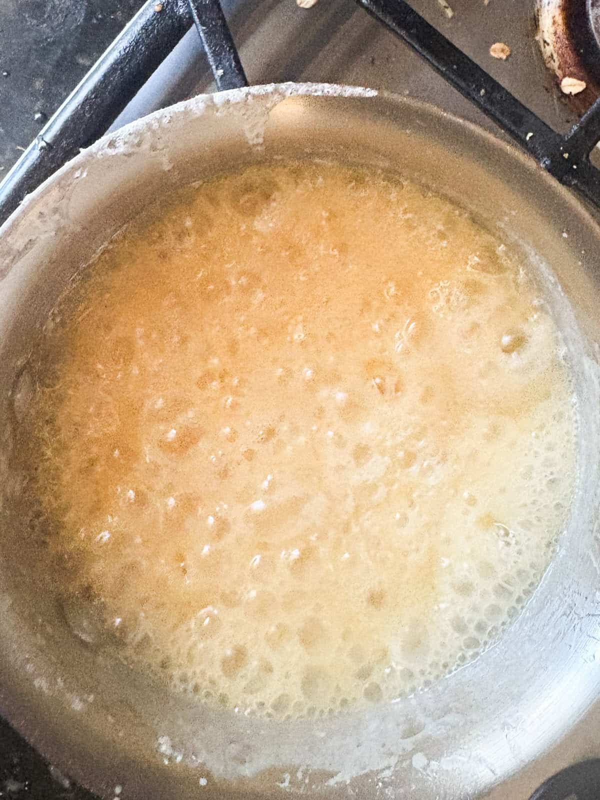 Silky and rich, this homemade salted caramel sauce is an absolute dream. Perfect over ice cream, waffles, cake, pancakes, and more. The sauces bubbles after adding the butter and cream.