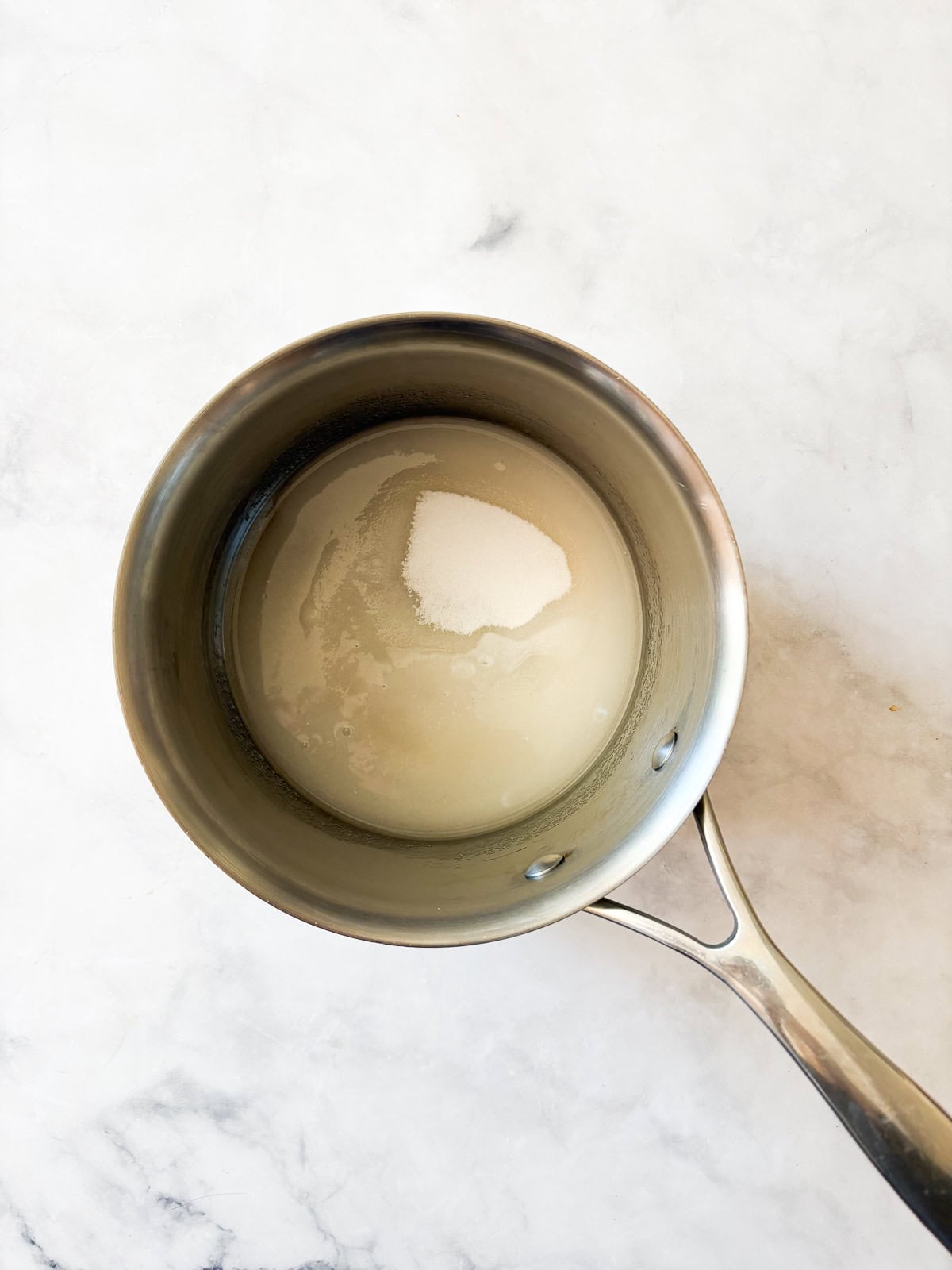 Silky and rich, this homemade salted caramel sauce is an absolute dream. Perfect over ice cream, waffles, cake, pancakes, and more. Sugar and water mixed in a pot.