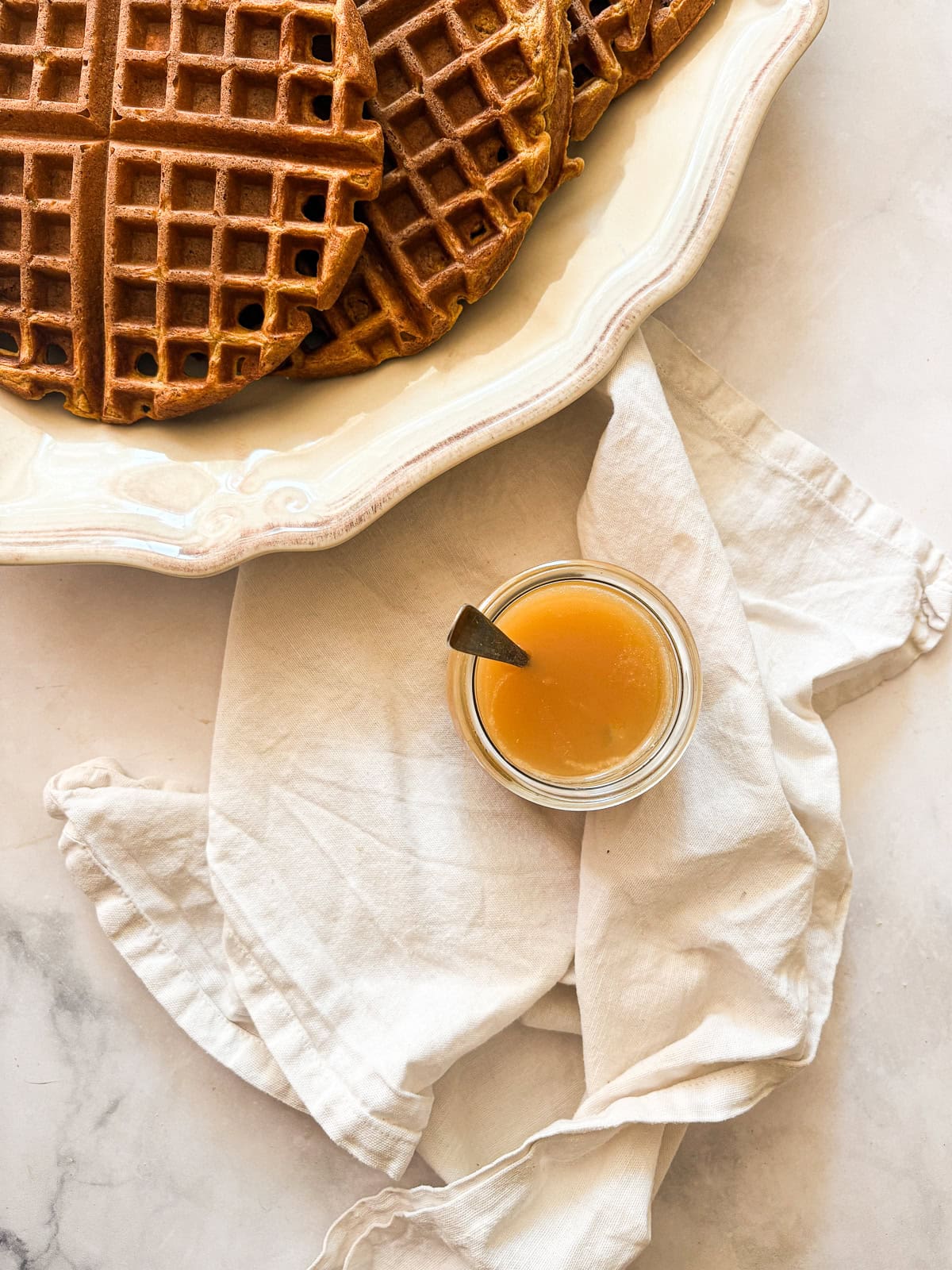 Silky and rich, this homemade salted caramel sauce is an absolute dream. Perfect over ice cream, waffles, cake, pancakes, and more. A jar of salted caramel sauce next to a plate of waffles.