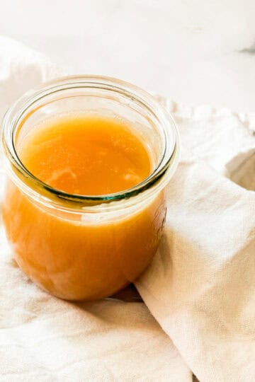 A glass jar of salted caramel sauce on a white napkin.