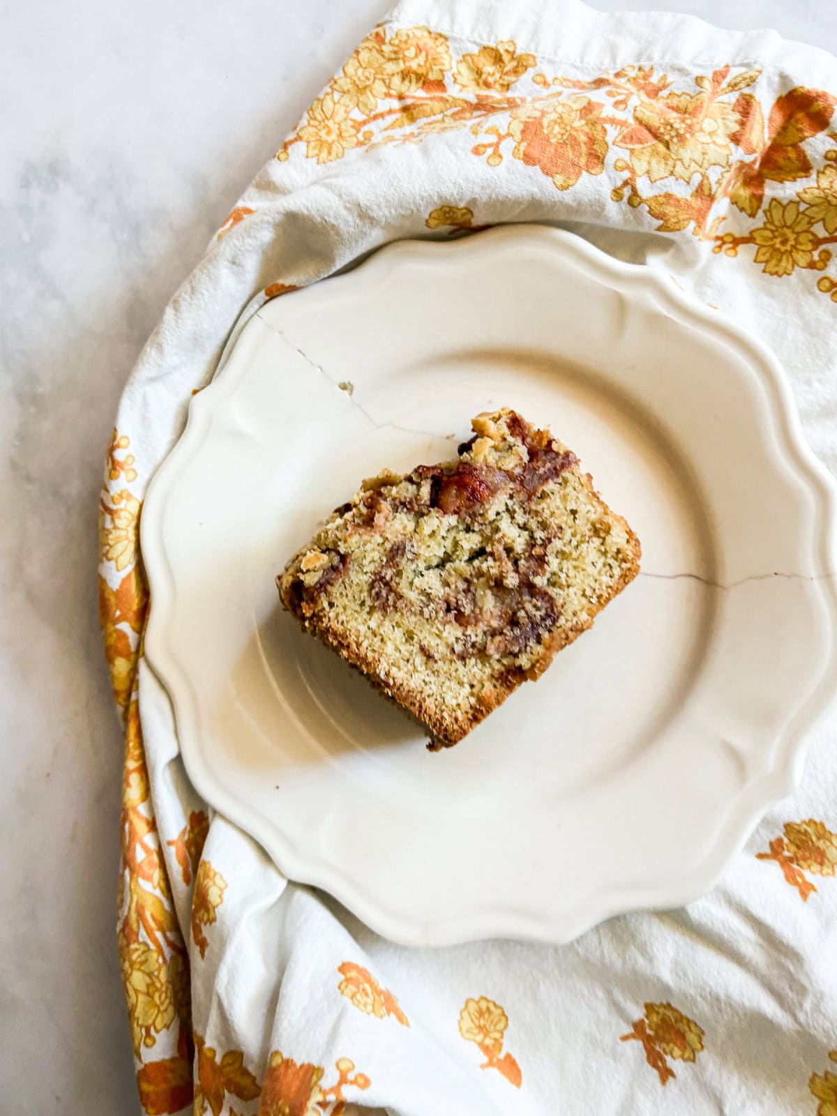 This homey gluten free one bowl apple cake is packed with whole-grain flour and juicy bites of cinnamon-spiked apples. Also dairy-free! A slice of one bowl apple cake on a plate.