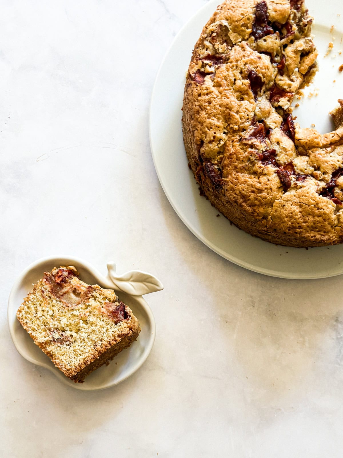 This homey gluten free one bowl apple cake is packed with whole-grain flour and juicy bites of cinnamon-spiked apples. Also dairy-free! A slice of apple cake on an apple plate next to the cake.