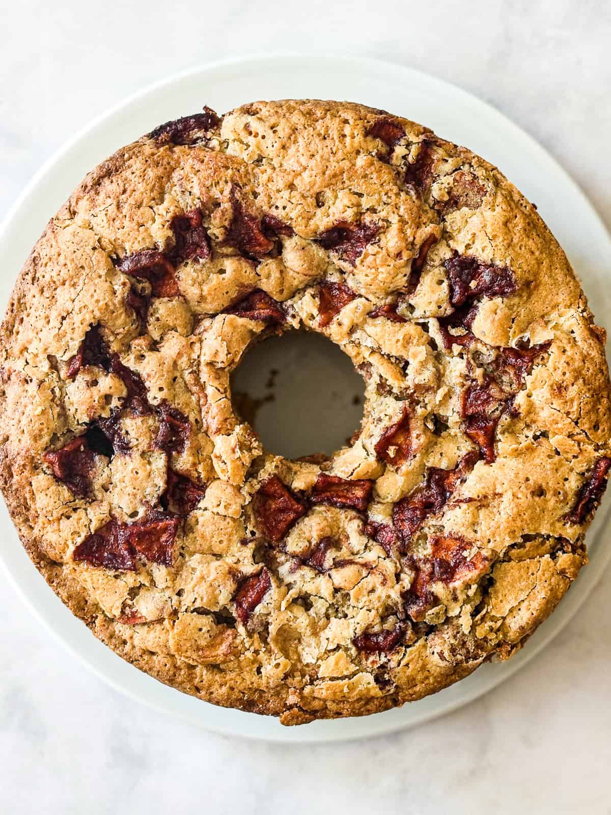 This homey gluten free one bowl apple cake is packed with whole-grain flour and juicy bites of cinnamon-spiked apples. Also dairy-free! A one bowl apple cake on a plate.