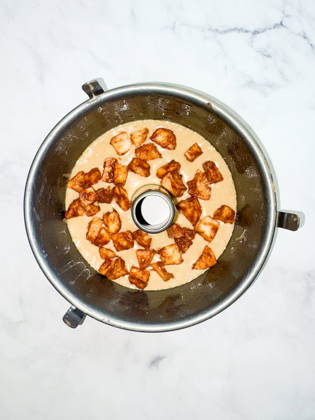 This homey gluten free one bowl apple cake is packed with whole-grain flour and juicy bites of cinnamon-spiked apples. Also dairy-free! Layering apples on top of cake batter.