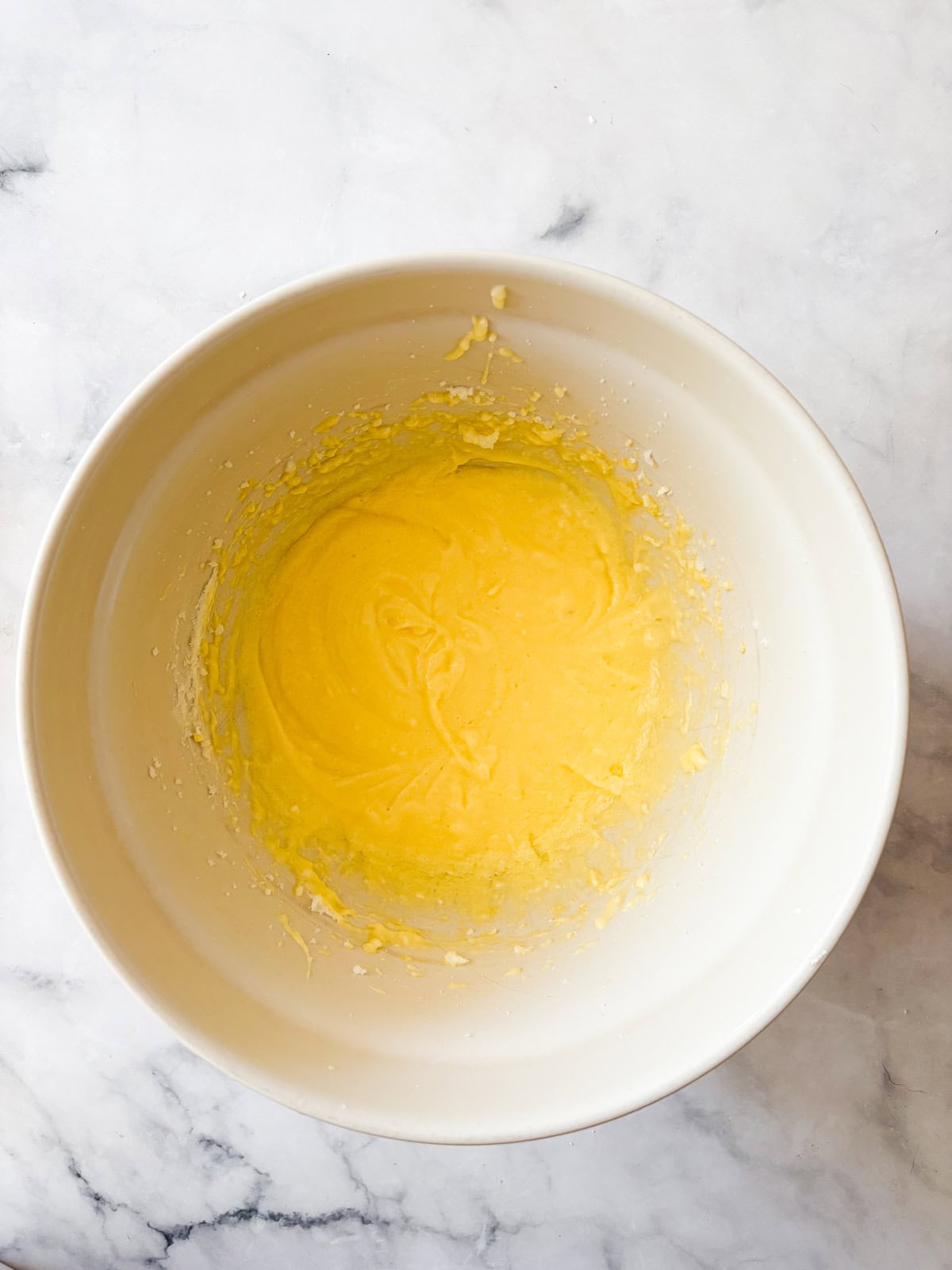 A tender gluten-free blackberry jam cake layered with whipped cream and jam that's fresh, light, and perfect for summer. Butter, sugar, and eggs mixed in a bowl.