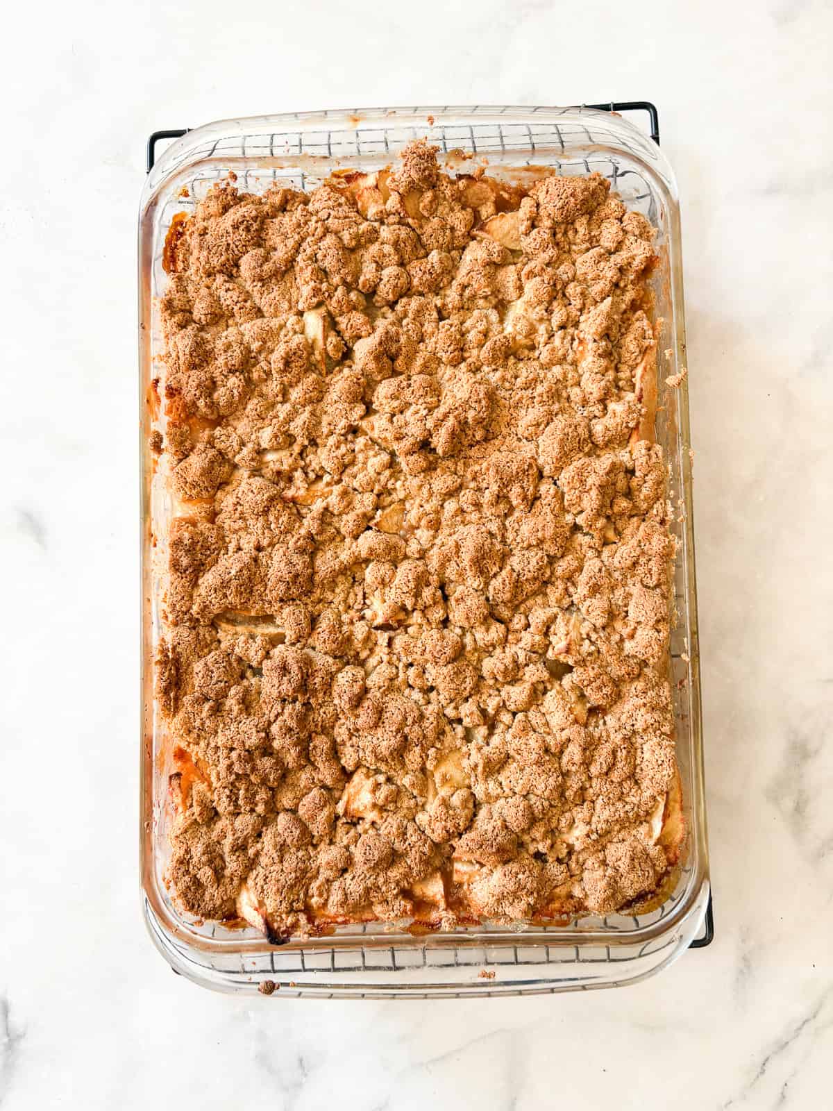 A crisp, buttery brown sugar streusel tops tender apples in this homey gluten free apple crumble. Perfect with vanilla ice cream! A gluten free apple crumble after being baked.