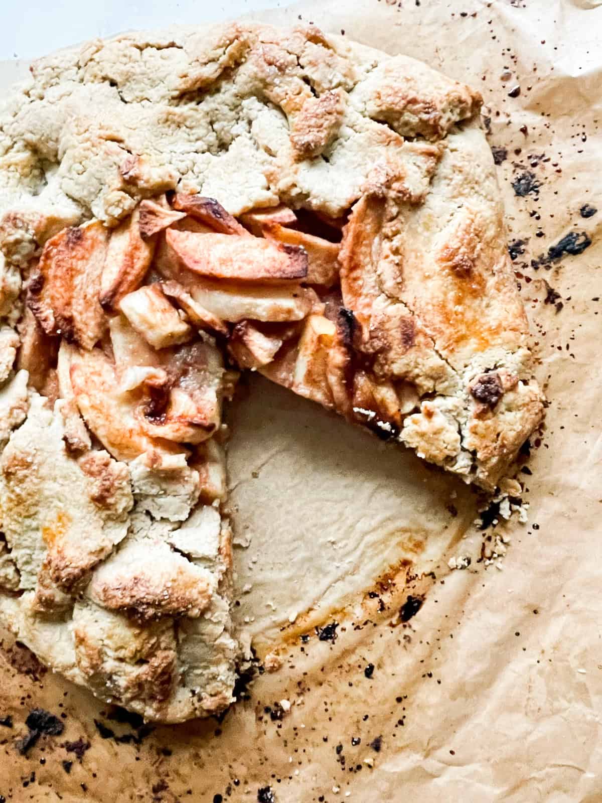 Rustic and beautiful, this gluten free apple galette wraps juicy, spiced apples in a buttery, flaky crust. Perfect for holiday gatherings! A gluten free apple galette with a slice cut out.