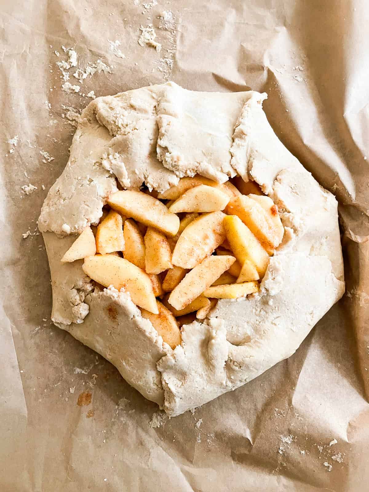 Rustic and beautiful, this gluten free apple galette wraps juicy, spiced apples in a buttery, flaky crust. Perfect for holiday gatherings! Gluten free crust wrapped around apples for a galette.