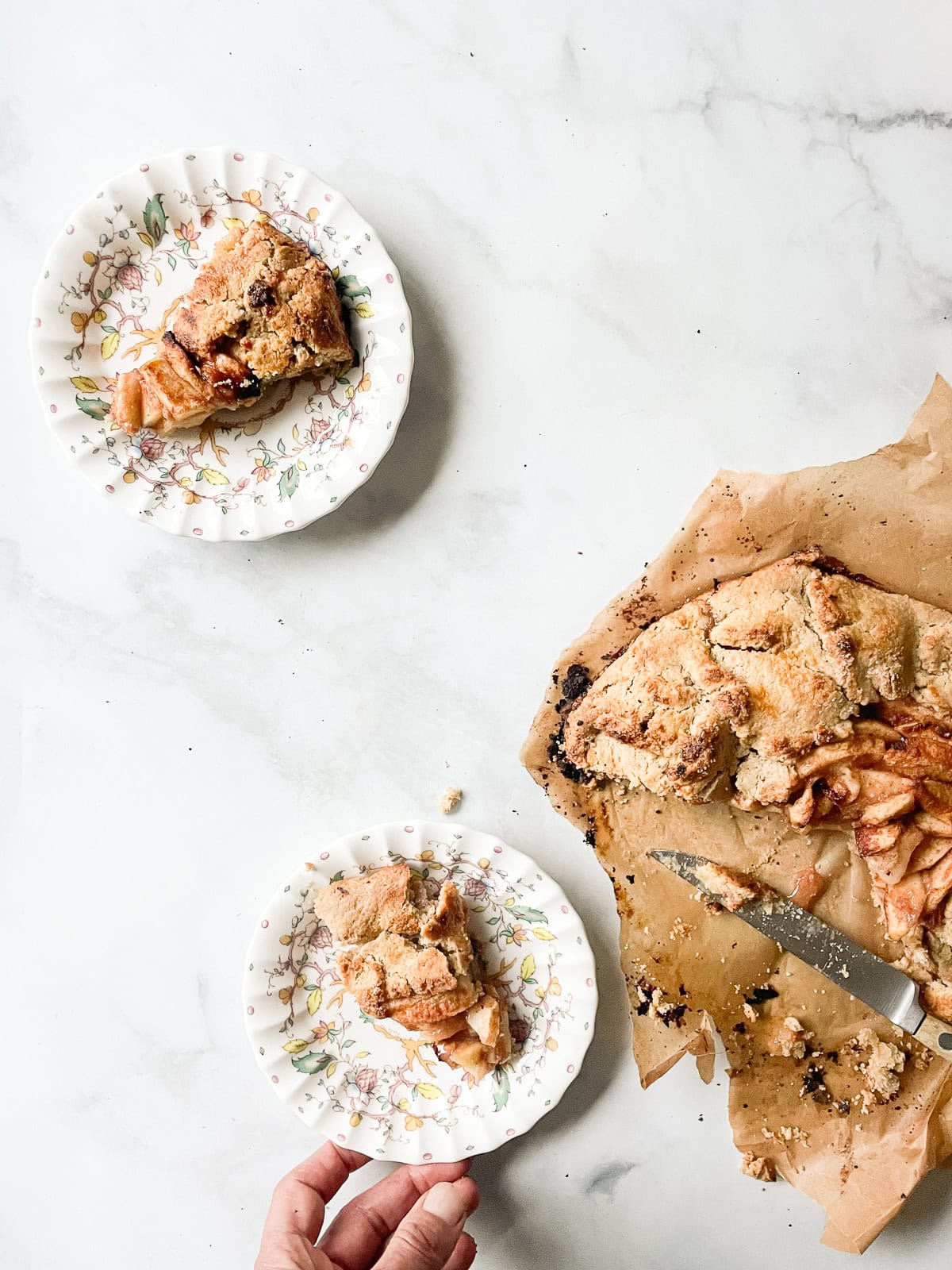 Rustic and beautiful, this gluten free apple galette wraps juicy, spiced apples in a buttery, flaky crust. Perfect for holiday gatherings! Slices of gluten free apple galette on plates.