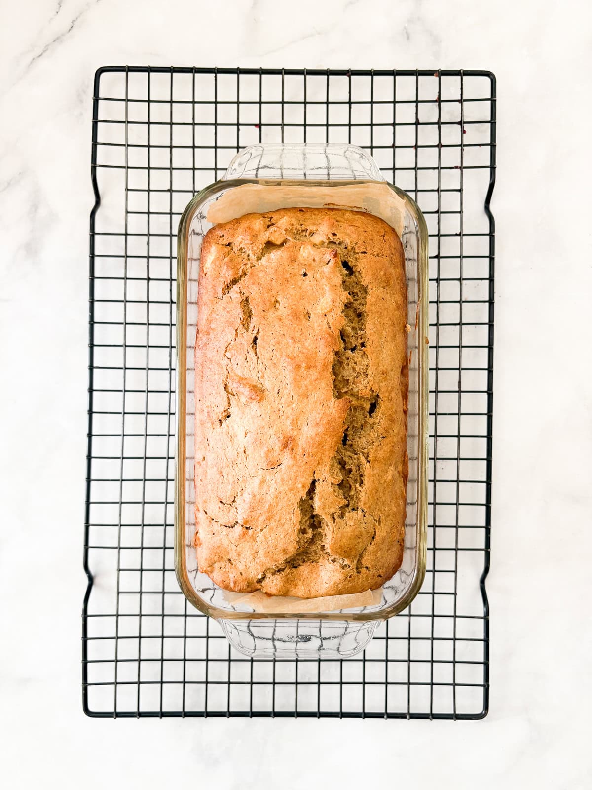 This beautifully simple yet deeply satisfying gluten free banana apple bread marries a classic banana bread with fresh for a twist. A loaf of gluten free banana apple bread cools in a pan.
