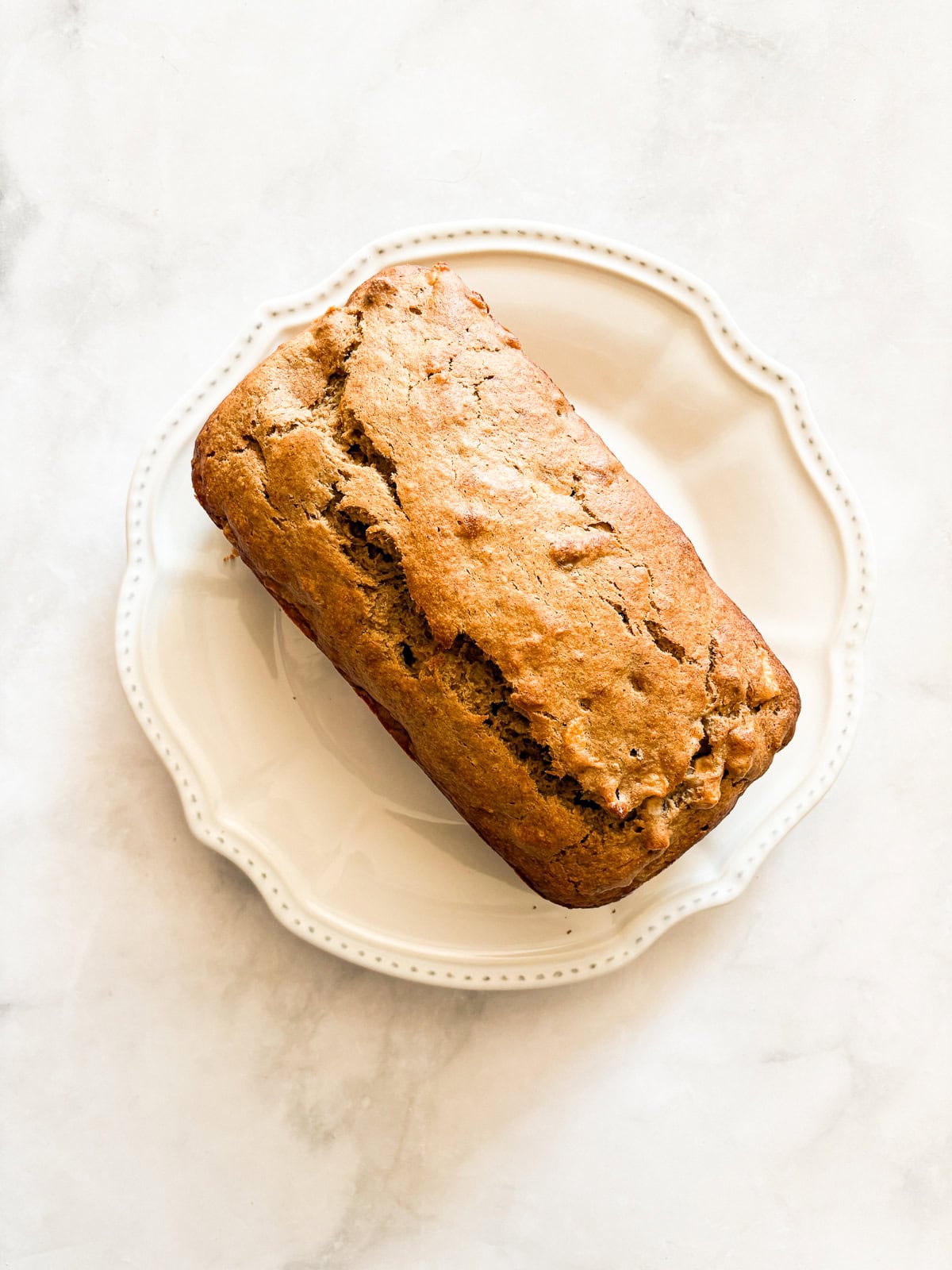 This beautifully simple yet deeply satisfying gluten free banana apple bread marries a classic banana bread with fresh for a twist. A loaf of gluten free banana apple bread on a plate.
