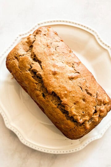 A loaf of gluten free banana apple bread on a plate.