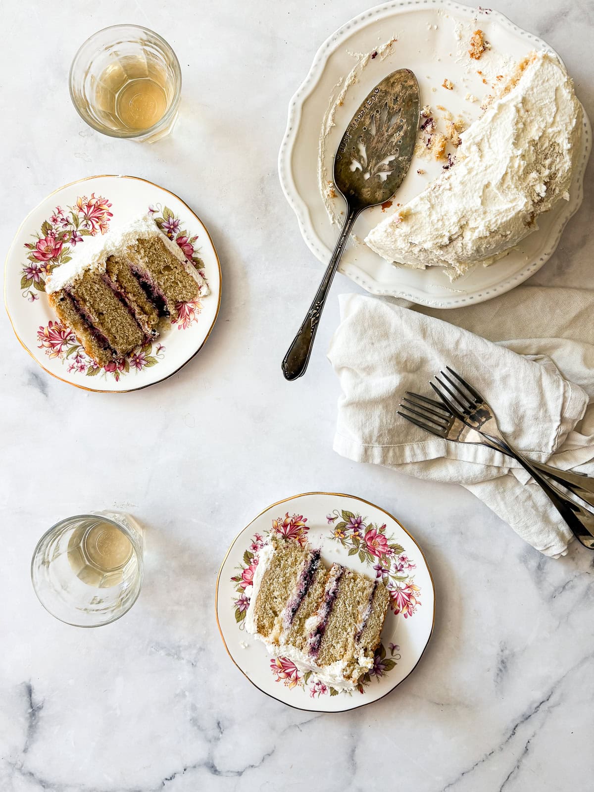 A tender gluten-free blackberry jam cake layered with whipped cream and jam that's fresh, light, and perfect for summer. Blackberry jam cake with glasses of sparkling wine.